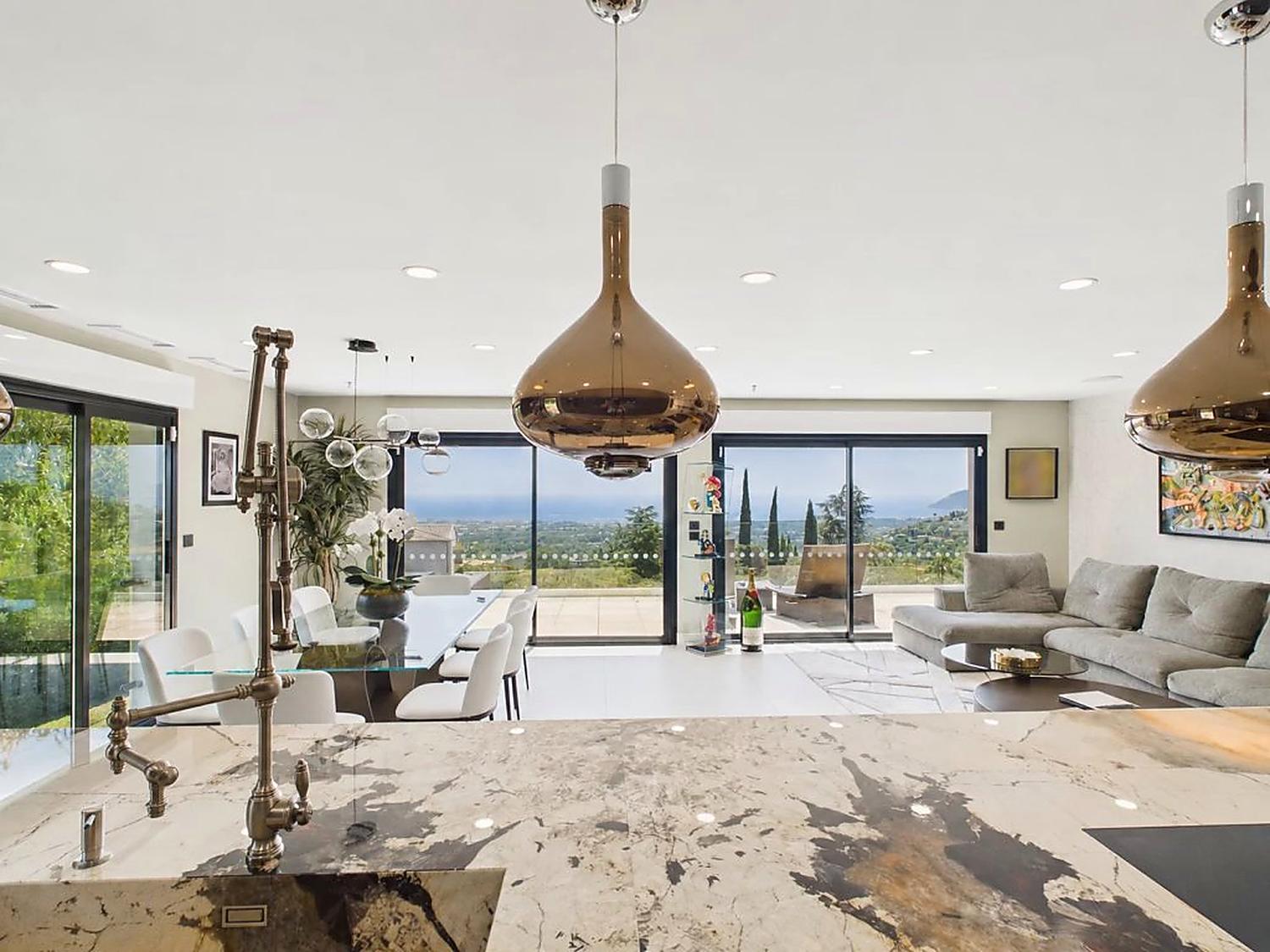 Open kitchen with copper pendant lights looking through to the living room and the sea