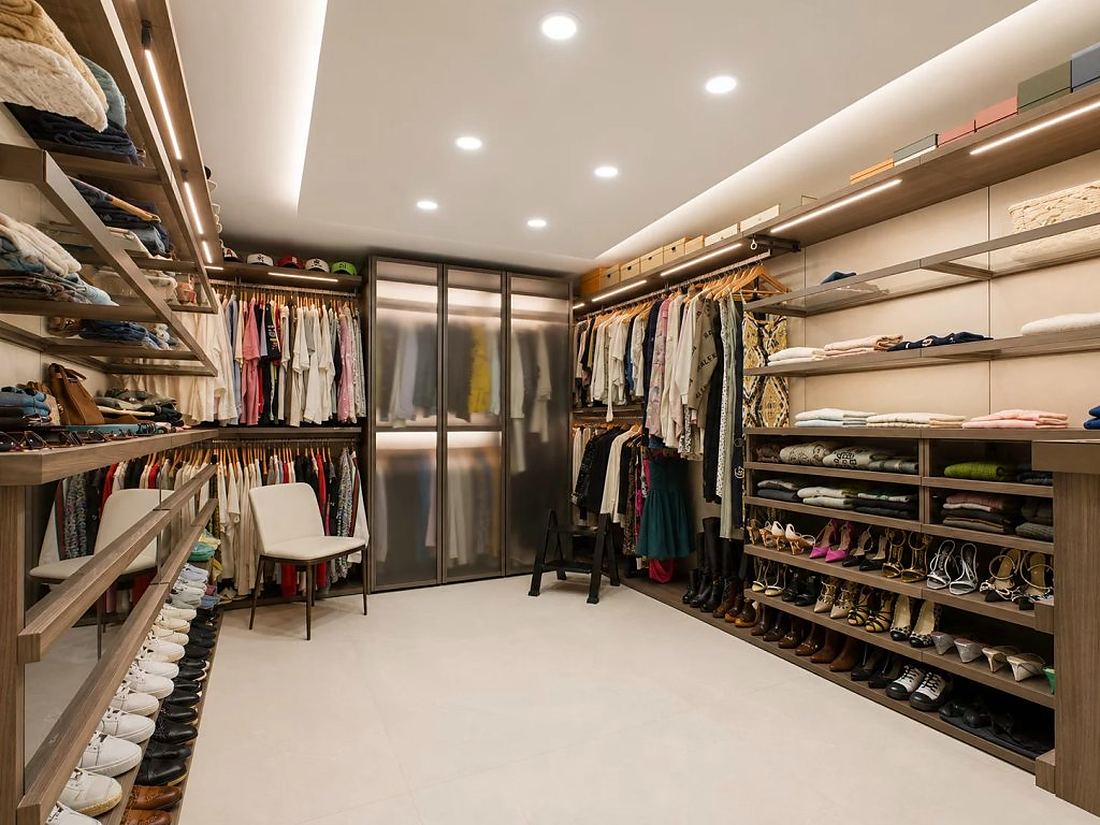 Very large walk-in dressing room with lit timber shelving